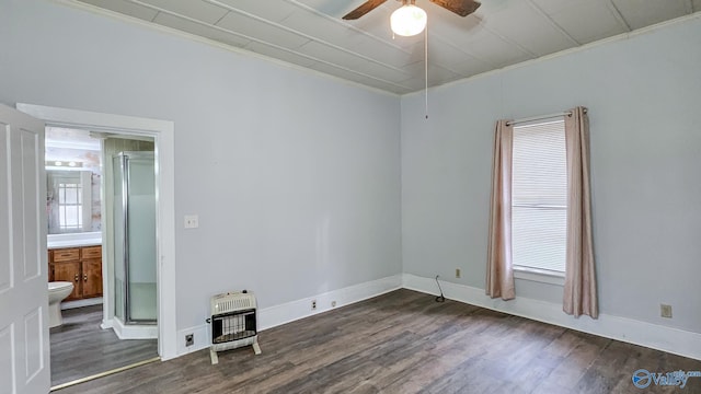 empty room featuring ceiling fan, dark hardwood / wood-style flooring, and heating unit