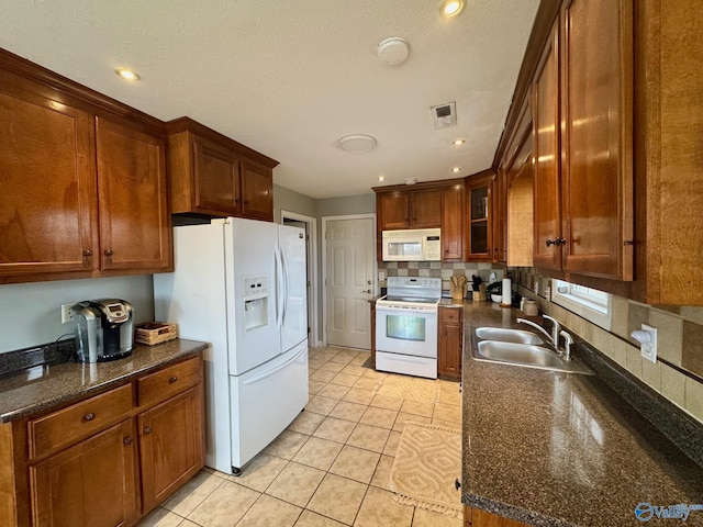 kitchen featuring light tile patterned floors, sink, white appliances, decorative backsplash, and dark stone counters