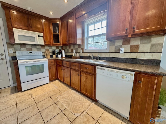 kitchen with light tile patterned flooring, white appliances, sink, and backsplash