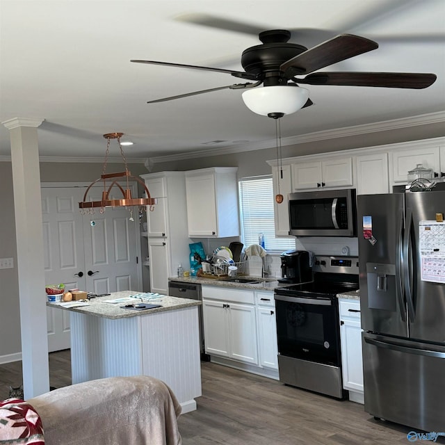 kitchen with light stone counters, appliances with stainless steel finishes, white cabinetry, wood-type flooring, and sink