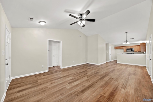 unfurnished living room featuring lofted ceiling, ceiling fan with notable chandelier, baseboards, and light wood-style floors