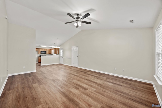 unfurnished living room featuring light wood finished floors, visible vents, vaulted ceiling, baseboards, and ceiling fan with notable chandelier