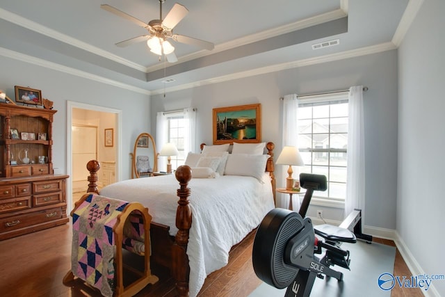 bedroom with ceiling fan, crown molding, hardwood / wood-style floors, and a tray ceiling