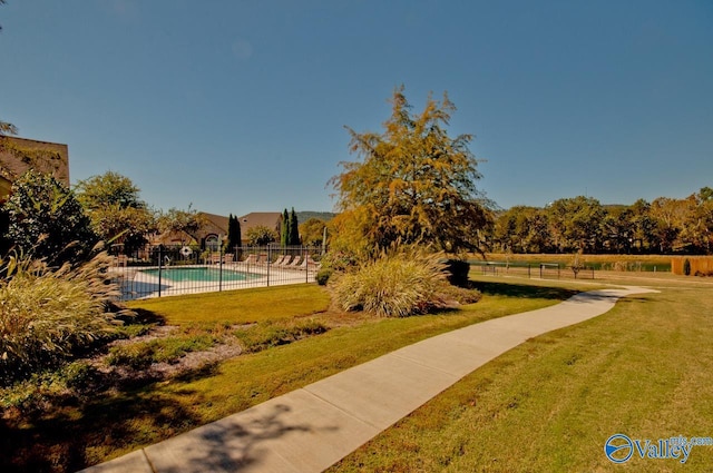 view of property's community with a swimming pool and a lawn