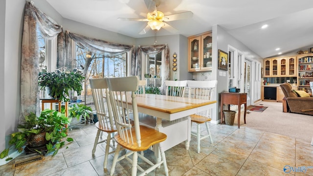 dining area with ceiling fan, vaulted ceiling, and light carpet