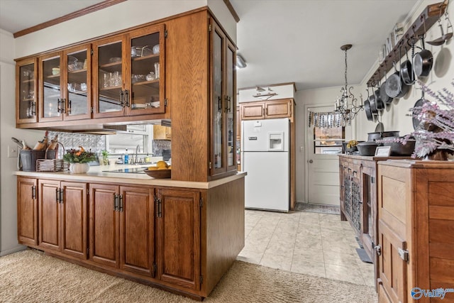 kitchen with light countertops, brown cabinetry, freestanding refrigerator, glass insert cabinets, and ornamental molding