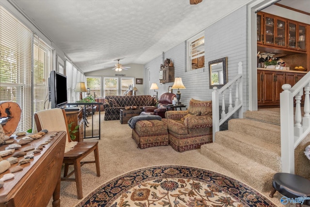 living room with a ceiling fan, carpet flooring, vaulted ceiling, a textured ceiling, and stairs