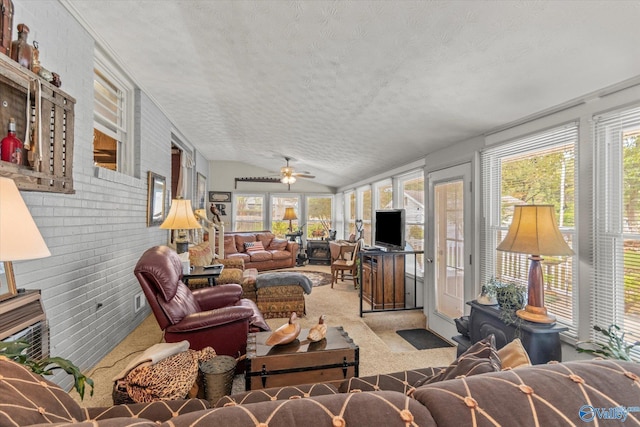 carpeted living room with a wealth of natural light, vaulted ceiling, a textured ceiling, and ceiling fan