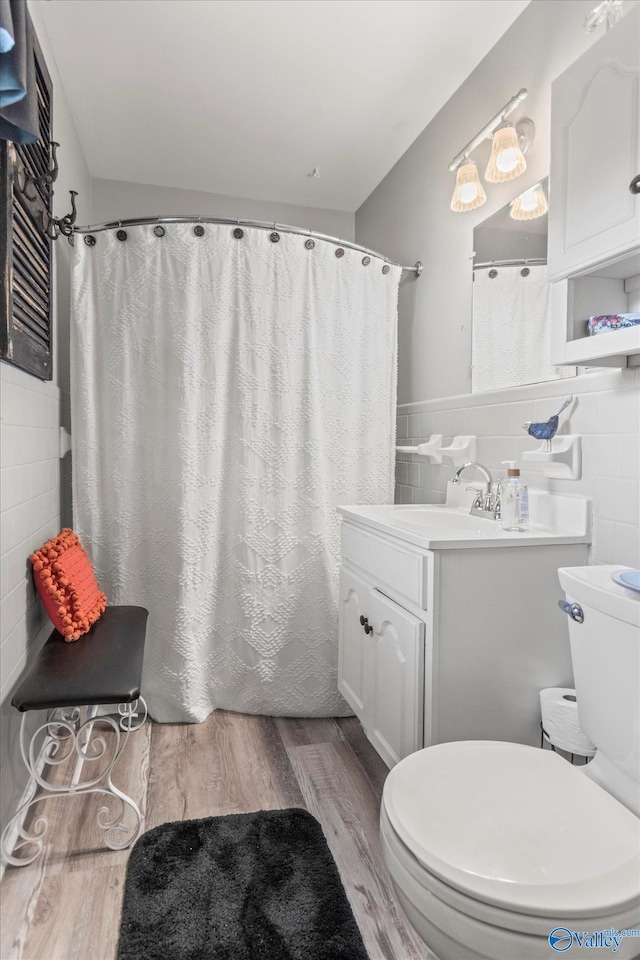 full bathroom with toilet, wood finished floors, vanity, tile walls, and a shower with curtain