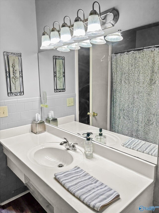 full bathroom featuring a shower with shower curtain, a wainscoted wall, tile walls, and vanity