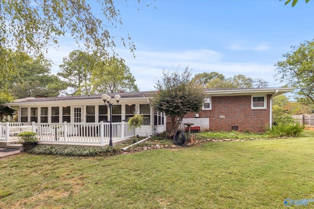 back of house with a sunroom, crawl space, brick siding, and a lawn