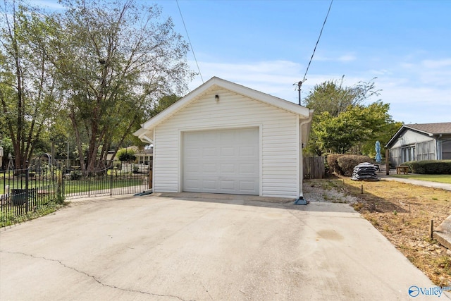 detached garage featuring fence and concrete driveway