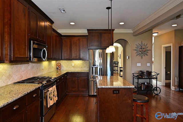 kitchen with a kitchen island, light stone countertops, stainless steel appliances, and dark wood-type flooring