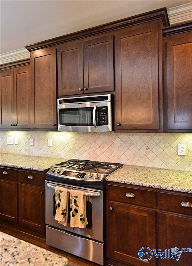 kitchen with dark brown cabinets, light stone counters, stainless steel appliances, and tasteful backsplash