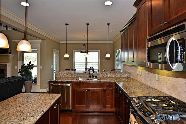 kitchen featuring sink, dark wood-type flooring, light stone counters, pendant lighting, and appliances with stainless steel finishes