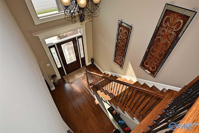 entryway featuring hardwood / wood-style floors, a towering ceiling, and an inviting chandelier