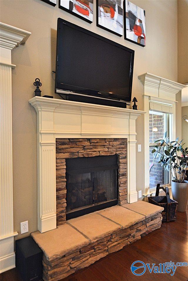 details with hardwood / wood-style floors and a stone fireplace