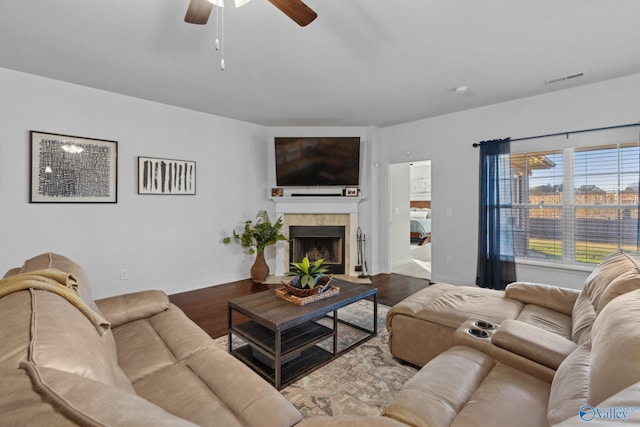 living room featuring a fireplace, wood-type flooring, and ceiling fan