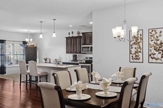 dining space featuring dark hardwood / wood-style floors, sink, and an inviting chandelier