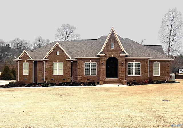 view of front of home featuring a shingled roof, crawl space, brick siding, and a front lawn