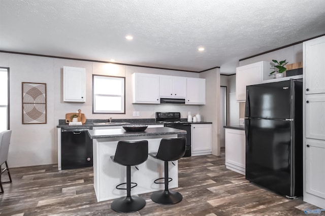 kitchen featuring a kitchen island, white cabinets, dark hardwood / wood-style flooring, and black appliances