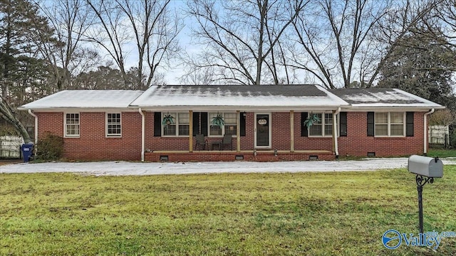 ranch-style home featuring covered porch and a front yard