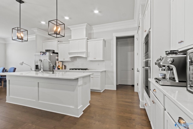 kitchen featuring pendant lighting, a kitchen island with sink, stainless steel appliances, and white cabinets