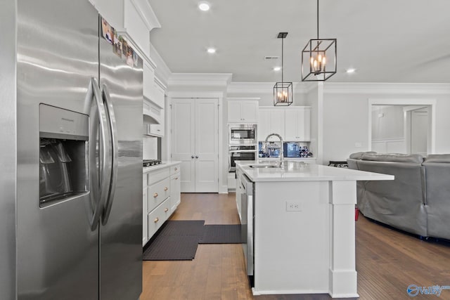 kitchen featuring pendant lighting, sink, stainless steel appliances, an island with sink, and white cabinets