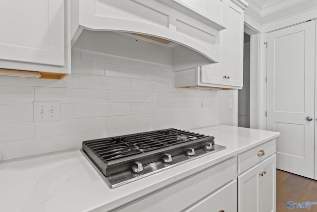 kitchen with dark wood-type flooring, custom range hood, white cabinets, decorative backsplash, and stainless steel gas stovetop