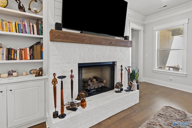 living room featuring crown molding, a brick fireplace, and dark wood-type flooring