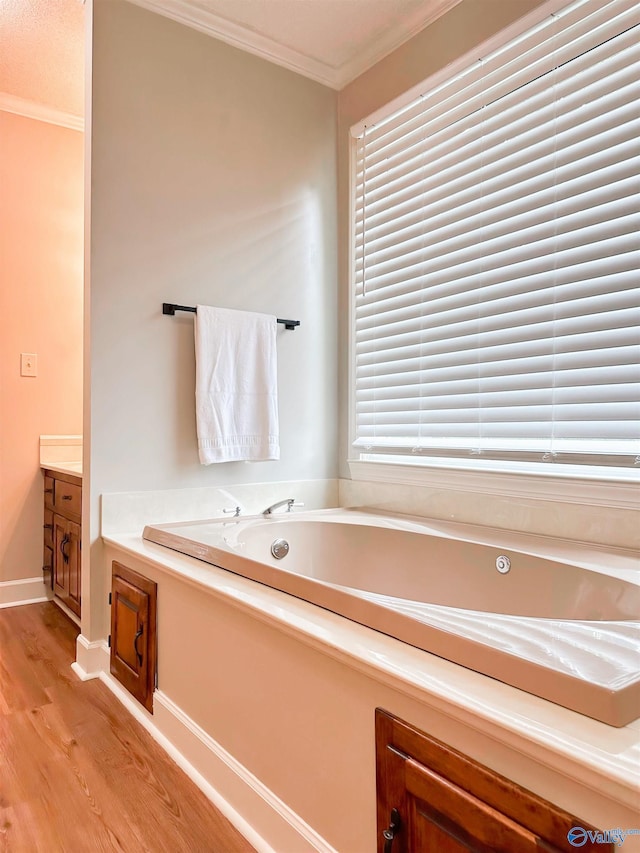 bathroom featuring a garden tub, crown molding, wood finished floors, and baseboards