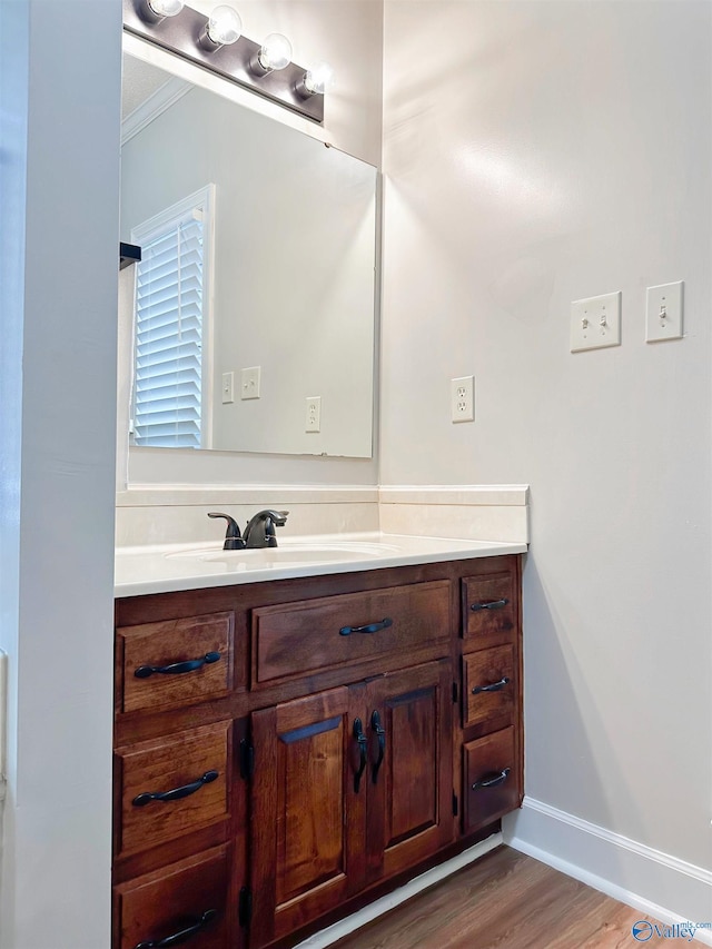 bathroom with baseboards, ornamental molding, vanity, and wood finished floors