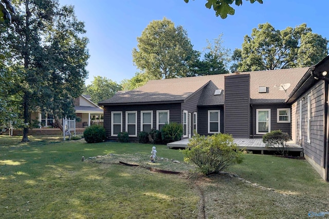 view of front of property featuring a wooden deck, a chimney, and a front yard