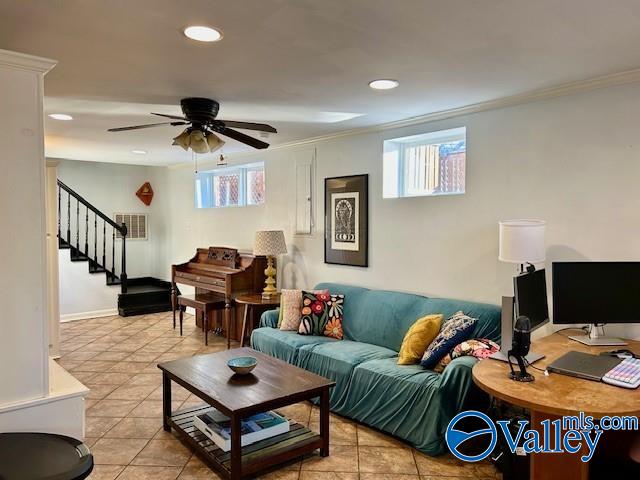 tiled living room with ceiling fan and crown molding