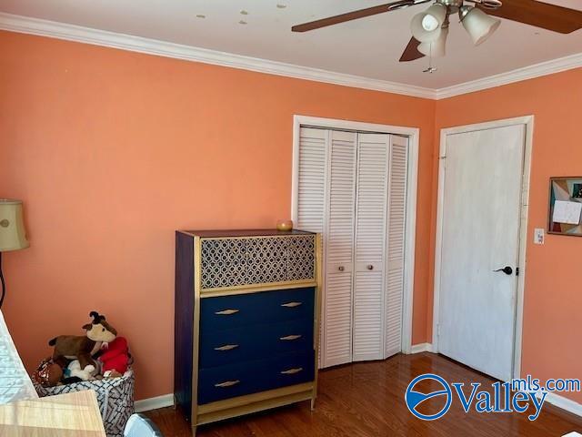 bedroom with dark hardwood / wood-style floors, ceiling fan, crown molding, and a closet