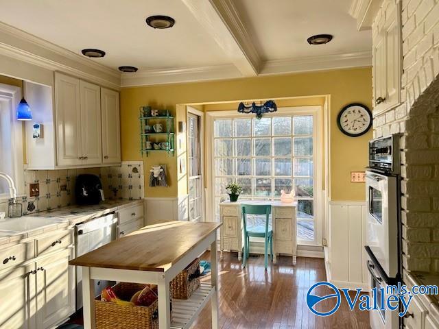 kitchen with dark wood-type flooring, sink, ornamental molding, a notable chandelier, and stainless steel appliances