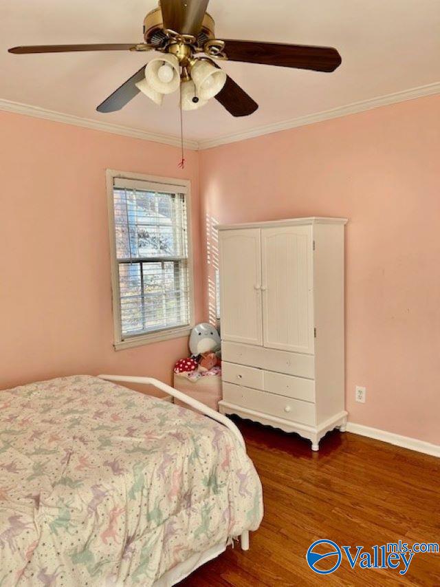 bedroom with ornamental molding, ceiling fan, and dark wood-type flooring