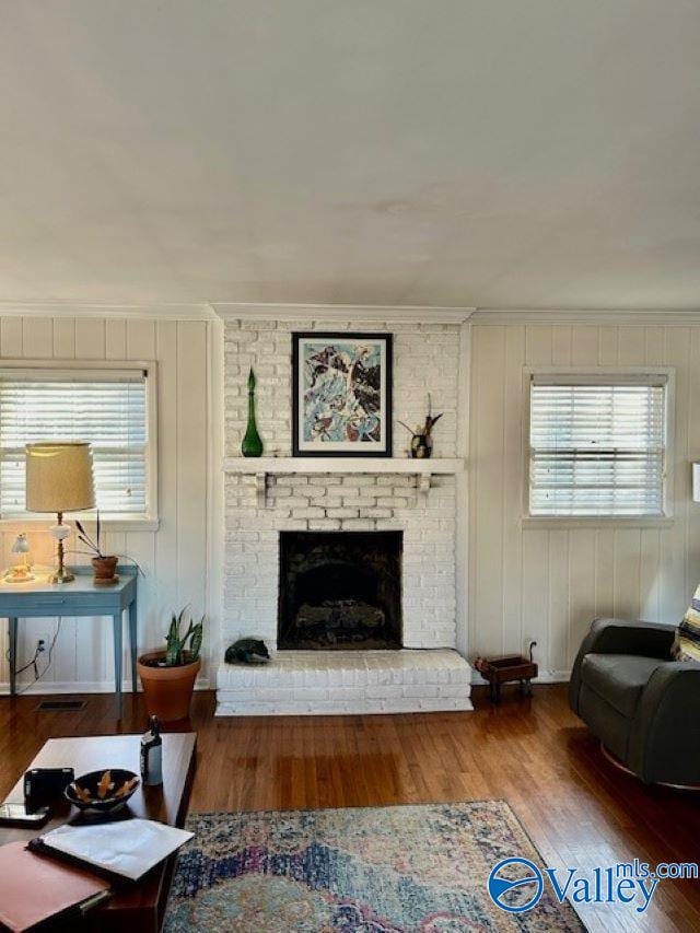 living room featuring a fireplace, crown molding, and hardwood / wood-style floors