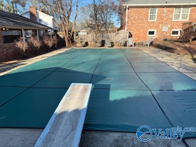 view of swimming pool featuring a patio area and a diving board