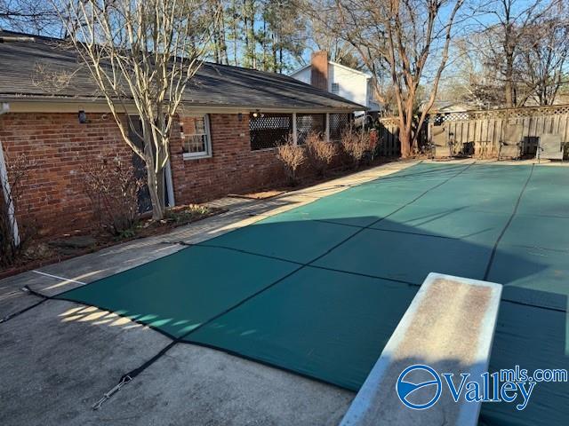 view of pool with a patio and a diving board