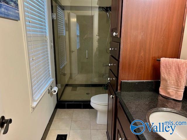 bathroom with tile patterned flooring, vanity, toilet, and a shower with shower door