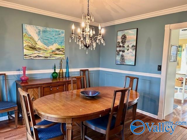 dining area with hardwood / wood-style floors, an inviting chandelier, and ornamental molding