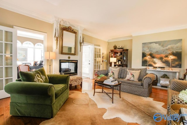 sitting room with a glass covered fireplace, wood finished floors, and ornamental molding