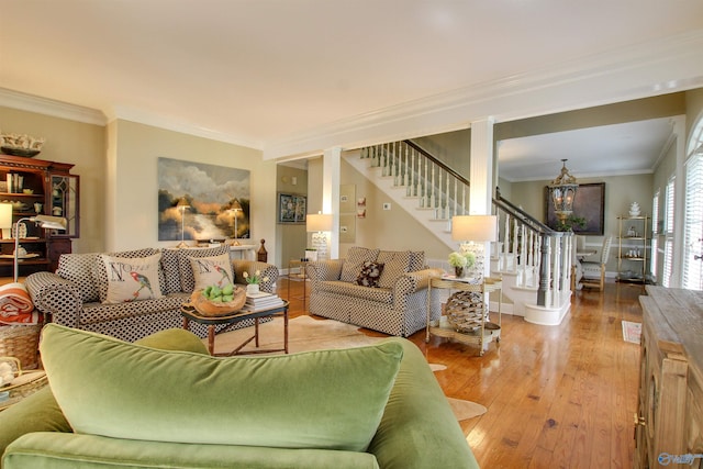 living room with hardwood / wood-style floors, baseboards, ornamental molding, stairs, and a notable chandelier