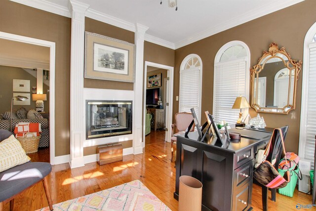 office with baseboards, a glass covered fireplace, ornamental molding, and light wood finished floors