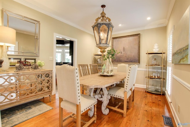 dining area featuring visible vents, baseboards, hardwood / wood-style floors, ornamental molding, and a notable chandelier