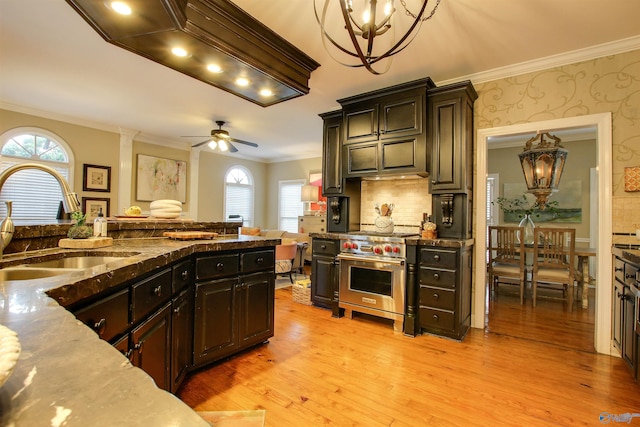 kitchen with designer range, light wood-style flooring, ornamental molding, a sink, and a wealth of natural light