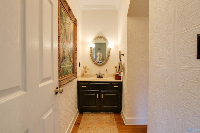 bathroom with wallpapered walls, crown molding, baseboards, and wood finished floors