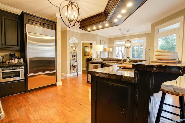 kitchen featuring a kitchen bar, a notable chandelier, appliances with stainless steel finishes, and ornamental molding