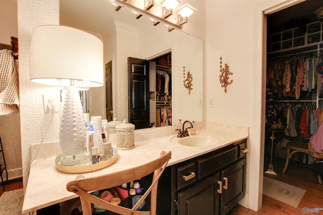 bathroom with a spacious closet, vanity, and wood finished floors